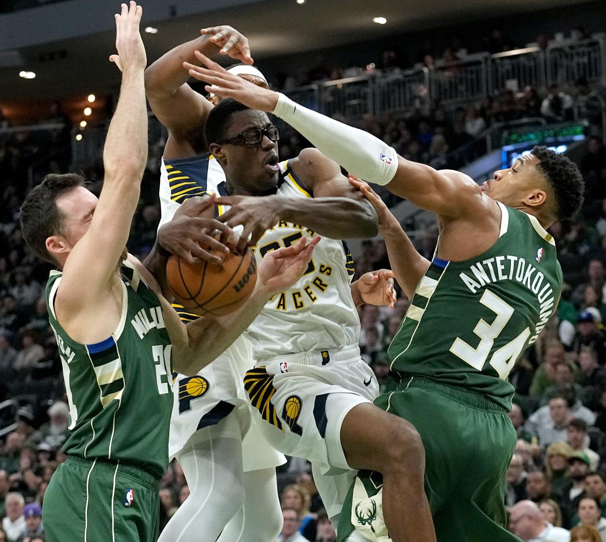 Indiana Pacers forward Jalen Smith (25) is shared by Milwaukee Bucks guard Pat Connaughton (24) and forward Giannis Antetokounmpo (34) during the first half of their game Monday, January 1, 2024 at Fiserv Forum in Milwaukee, Wisconsin.