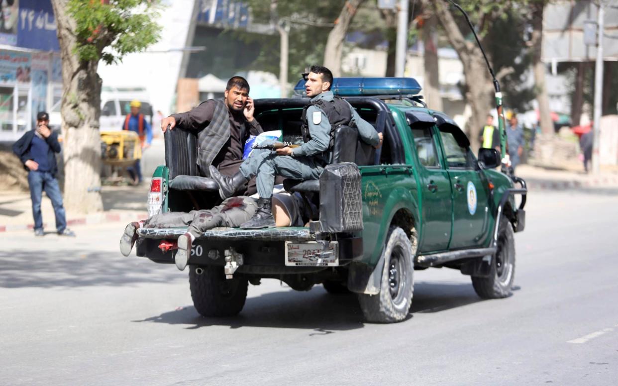Afghan security personnel carry a victim after the second blast - AP