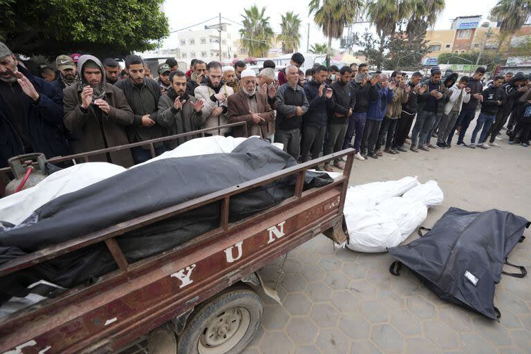 Los palestinos rezan por los cuerpos de sus familiares muertos en los bombardeos israelíes de la Franja de Gaza frente a la morgue en el Hospital Al Aqsa en Deir al Balah el viernes 23 de febrero de 2024