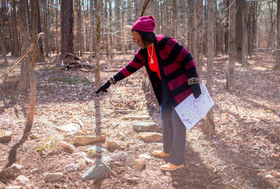 Retired Judge Beverly Scarlett points out some of the Indigenous burial rocks arranged in the woods near her home in Hillsborough, N.C. on Wednesday, Feb. 15, 2022. The slave cemetery was discovered later in the spring.
