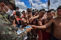 En la fotografía, un soldado reparte mascarillas a indígenas yanomami en la aldea de Surucucu. (Foto: Nelson Almeida / AFP / Getty Images).