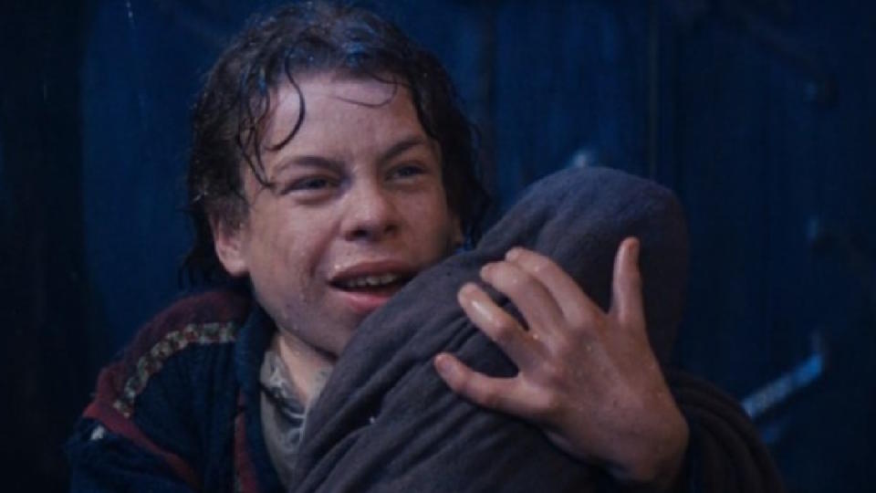 Warwick Davis holds a baby in Disney's Willow