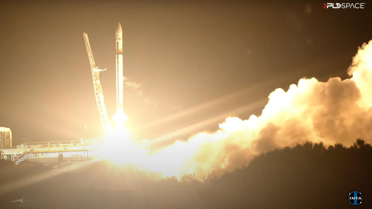  A white rocket launches into a night sky. 