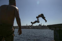 Backdropped by the historical Suleymaniye mosque youths jump from the Galata Bridge into the Golden Horn leading to the Bosphorus Strait separating Europe and Asia, in Istanbul, Friday, May 14, 2021. Turkey is in the final days of a full coronavirus lockdown and the government has ordered people to stay home and businesses to close amid a huge surge in new daily infections. But millions of workers are exempt and so are foreign tourists. Turkey is courting international tourists during an economic downturn and needs the foreign currencies that tourism brings to help the economy as the Turkish lira continues to sink. (AP Photo/Emrah Gurel)