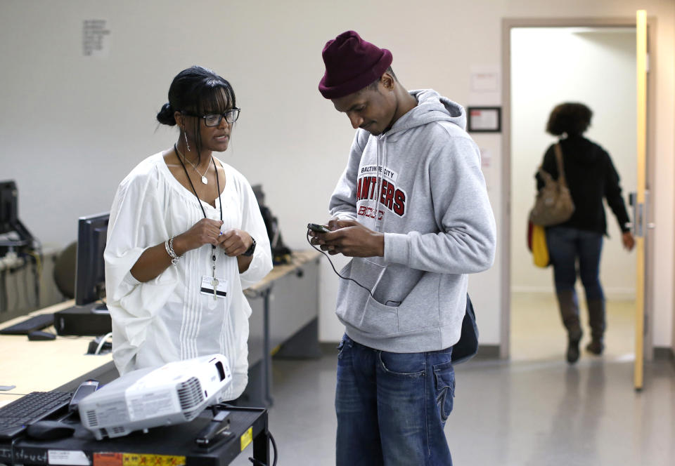 This photo taken March 12, 2014, shows developmental reading professor Naesea Price, left, giving student Rahman Hassan information on her office hours after a remedial English course at Baltimore City Community College in Baltimore. Only about a quarter of students nationally who take developmental _ or remedial _ classes ever graduate. The problem is so profound that the advocacy group Complete College America dubs remedial classes the “bridge to nowhere.” The challenge, educators say, is that even as billions is spent annually on remedial classes, many of these students run out of financial aid before they can complete their credit requirements, get discouraged by non-credit classes or find themselves unable to complete them. The Baltimore school is one of several places around the country looking to improve the odds for these students. (AP Photo/Patrick Semansky)