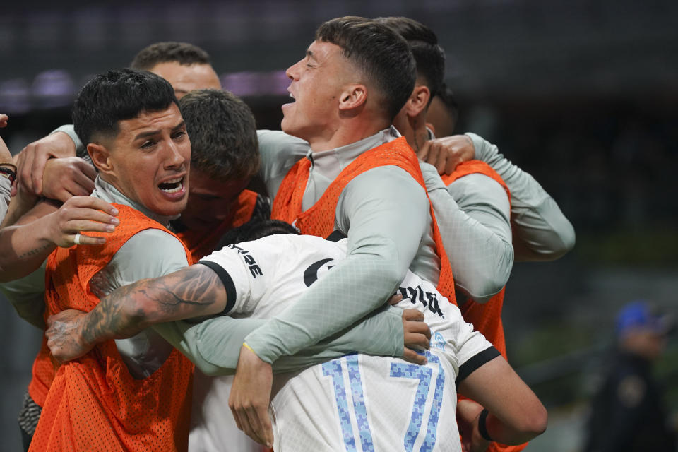 El estadounidense Alejandro Zendejas es felicitado por sus compañeros en la banca, luego de anotar ante Cruz Azul, el sábado 15 de abril de 2023, en el Estadio Azteca (AP Foto/Fernando Llano)