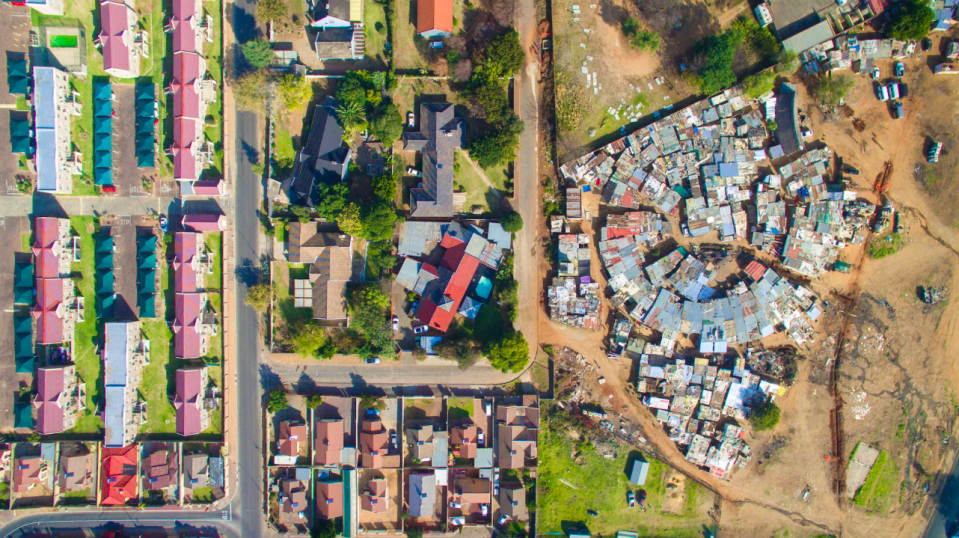 <p>Spacious mansions sit just across the road from where people live in poverty in South Africa (MediaDrumWorld/Johnny Miller) </p>