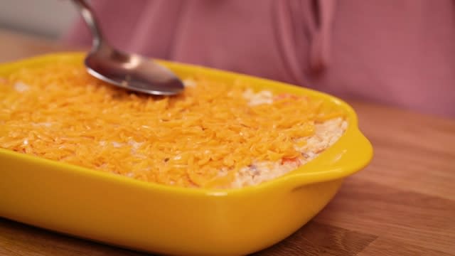 smoothing cheese with spoon on top of baked rice