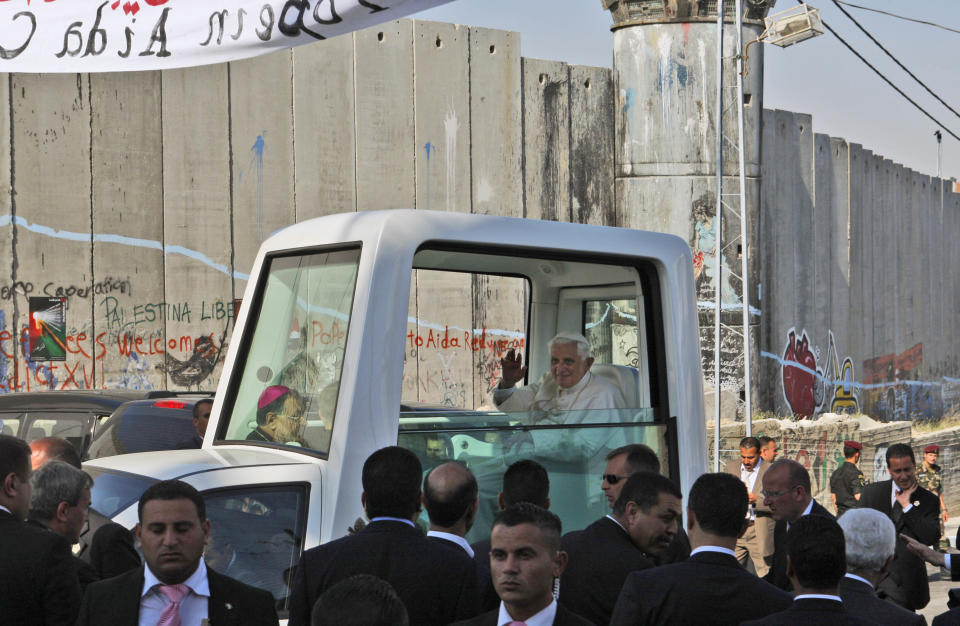 FILE - Pope Benedict XVI waves to Palestinians as he arrives for a ceremony at the Aida Refugee Camp, backdropped by the separation barrier in the West Bank town of Bethlehem on May 13, 2009. Pope Emeritus Benedict XVI, the German theologian who will be remembered as the first pope in 600 years to resign, has died, the Vatican announced Saturday. He was 95. (AP Photo/Muhammed Muheisen, File)