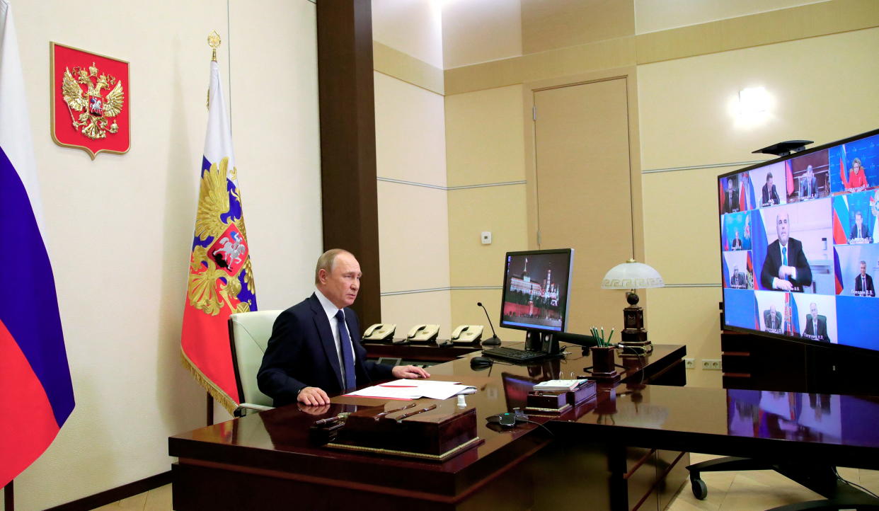 Russian President Vladimir Putin sits at a desk during a meeting via video link.