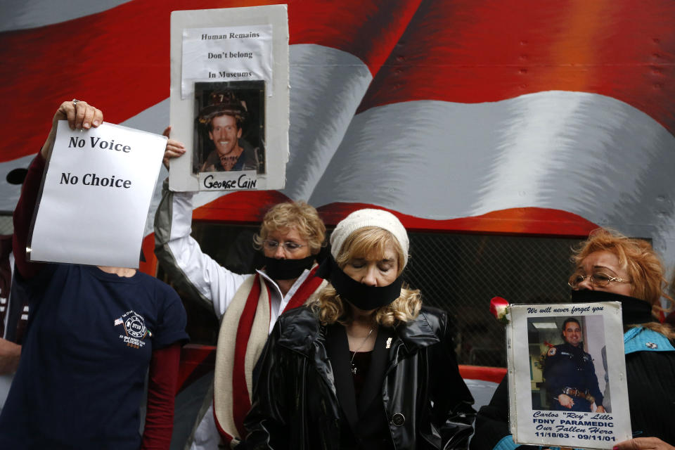 Family members of victims of the Sept. 11, 2001 attacks tie black gags over their mouths in protest of the transfer of unidentified remains of those killed at the World Trade Center from the Office of the Chief Medical Examiner to the World Trade Center site, Saturday, May 10, 2014, in New York. The remains will be transferred to an underground repository in the same building as the National September 11 Memorial Museum. (AP Photo/Jason DeCrow)