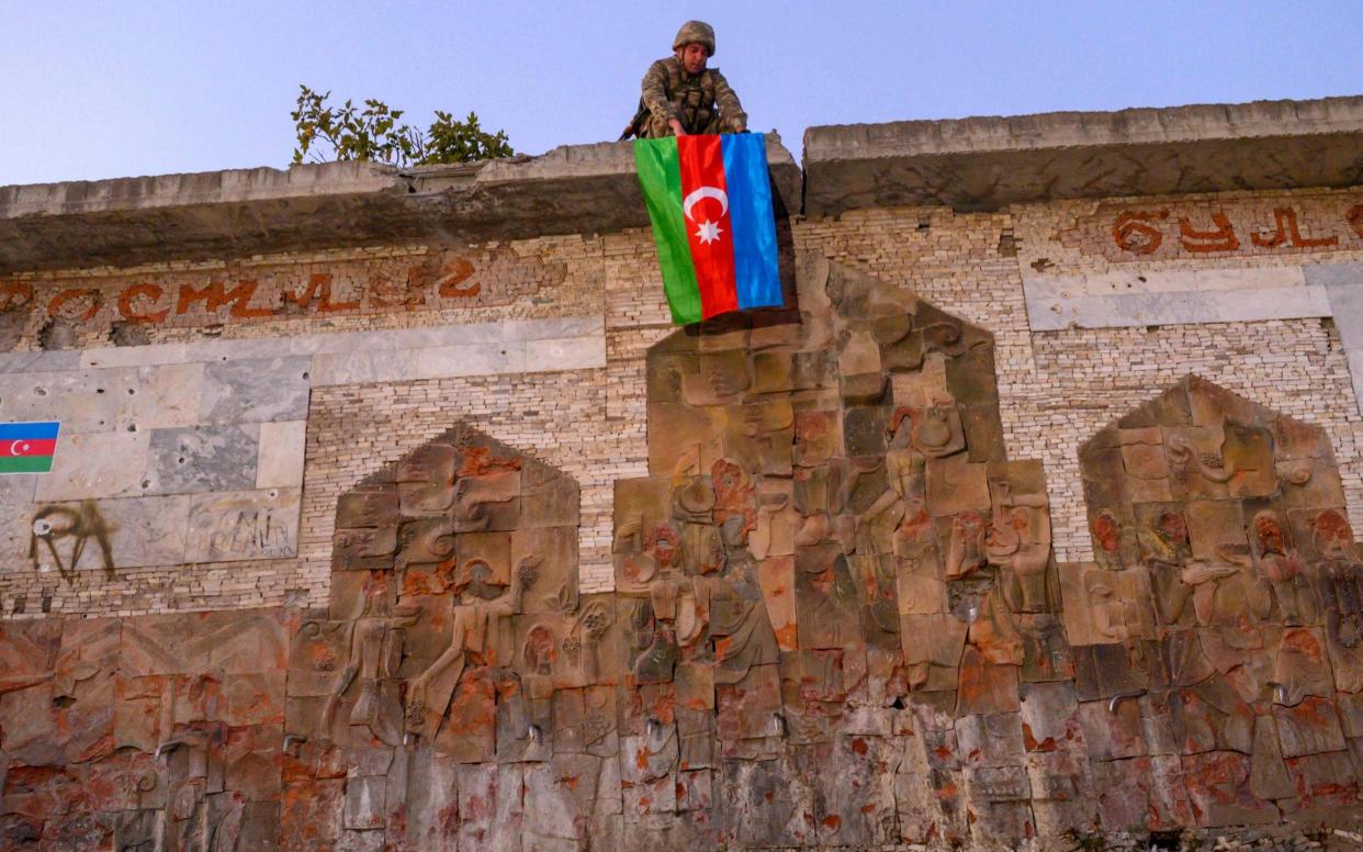 An Azeri soldier hangs the flag of Azerbaijan in the city of Jabrayil, where Azeri forces regained control during the fighting with Armenia over the breakaway region of Nagorno-Karabakh on October 16, 2020. - AFP/An Azeri soldier hangs the flag of Azerbaijan in the city of Jabrayil, where Azeri forces regained control during the fighting with Armenia over the breakaway region of Nagorno-Karabakh on October 16, 2020.