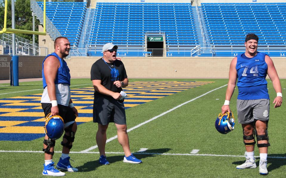 SDSU guard Mason McCormick (left) and tackle Garret Greenfield (74) share a laugh with assistant coach Ryan Olson during a break Friday at Dana J. Dykhouse Stadium.
