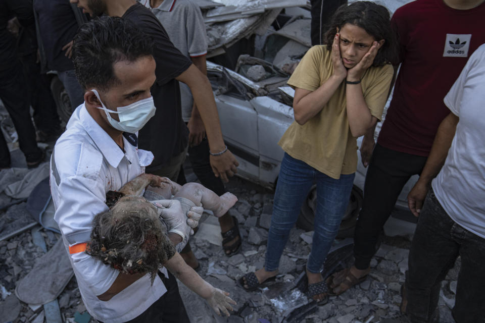 A Palestinian girl reacts as a child is carried from the rubble of a building after an airstrike in Khan Younis, Gaza Strip, Saturday, Oct. 21, 2023. (AP Photo/Fatima Shbair)