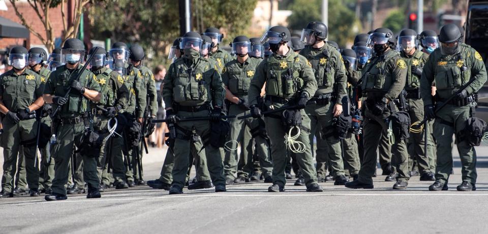 Orange County Sheriff deputies line up as Black Lives Matter protesters and counter protesters clash in Yorba Linda, Calif., Saturday, Sept. 26, 2020. Police eventually declared the event an unlawful gathering and cleared the streets near Yorba Linda and Imperial. Authorities said people were struck by a car and injured during the Black Lives Matter protest and counter protest about 30 miles southeast of Los Angeles. Orange County Sheriff's Department spokeswoman Carrie Braun says the injured were transported to a hospital with non-life-threatening injuries and the driver was detained. (Mindy Schauer/The Orange County Register via AP)