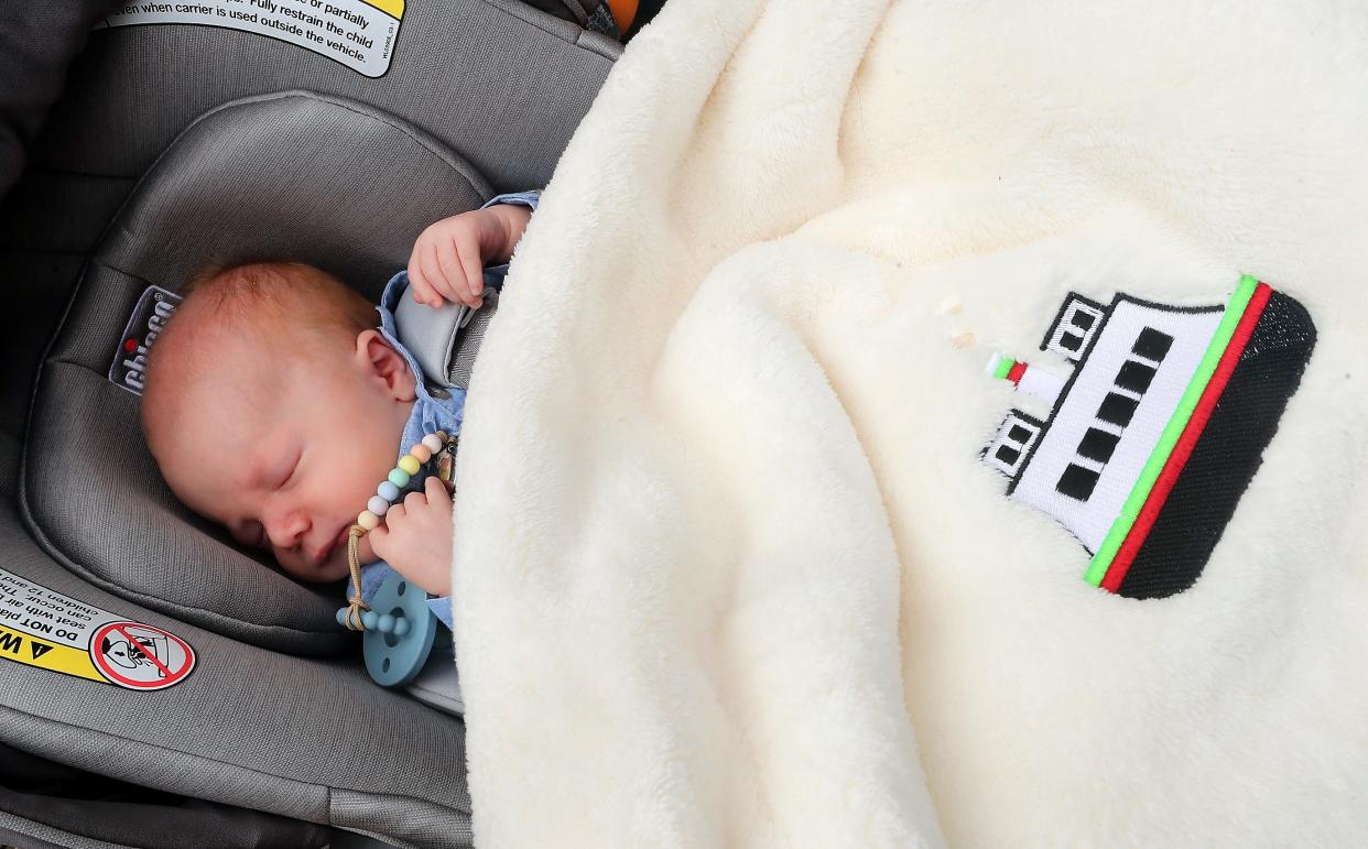 Charlie Wetzel naps in his car seat with a ferry blanket that his "Ferry Godmother" Tara Kenneway gifted him, as the family talks about Charlie's unexpected arrival in the ferry lanes, at Bainbridge Island's Waterfront Park on May 19.