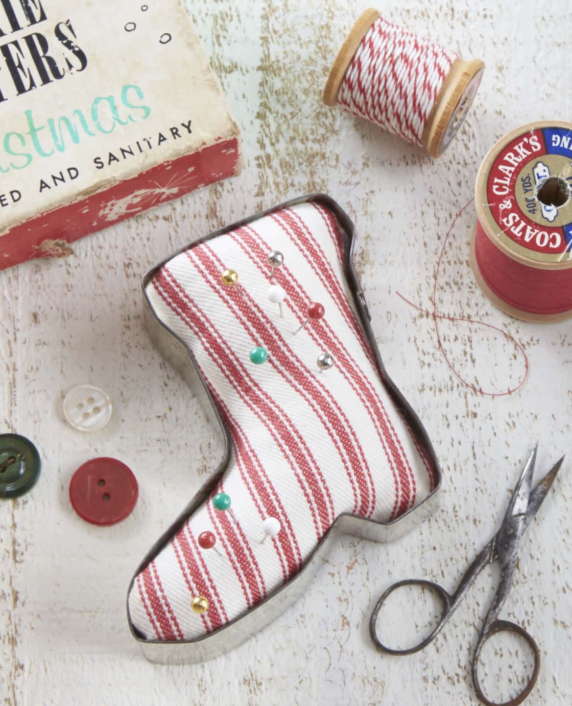 a vintage santa boot shaped cookied cutter turned into a pin cushion using red and white ticking striped fabric