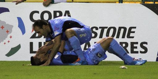 Juan Arce, del Bolívar, celebra un gol ante el León de México junto a su compañero José Capdevila (encima) durante la ida de los octavos de final de la Copa Libertadores, disputada en León, el 16 de abril de 2014 (AFP | ADID JIMENEZ)