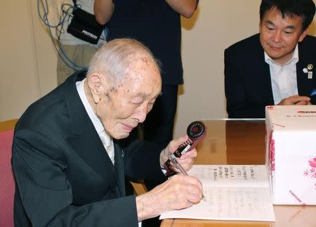 Sakari Momoi (L), a resident of Saitama prefecture, writes a message to communicate with Saitama Mayor Hayato Shimizu (R) in Tokyo, in this Kyodo file photo taken September 2013. Mandatory credit REUTERS/Kyodo/Files