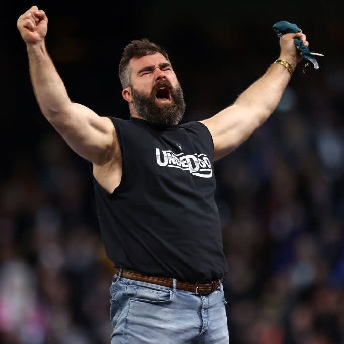 Jason Kelce cheers with arms raised, wearing a sleeveless 