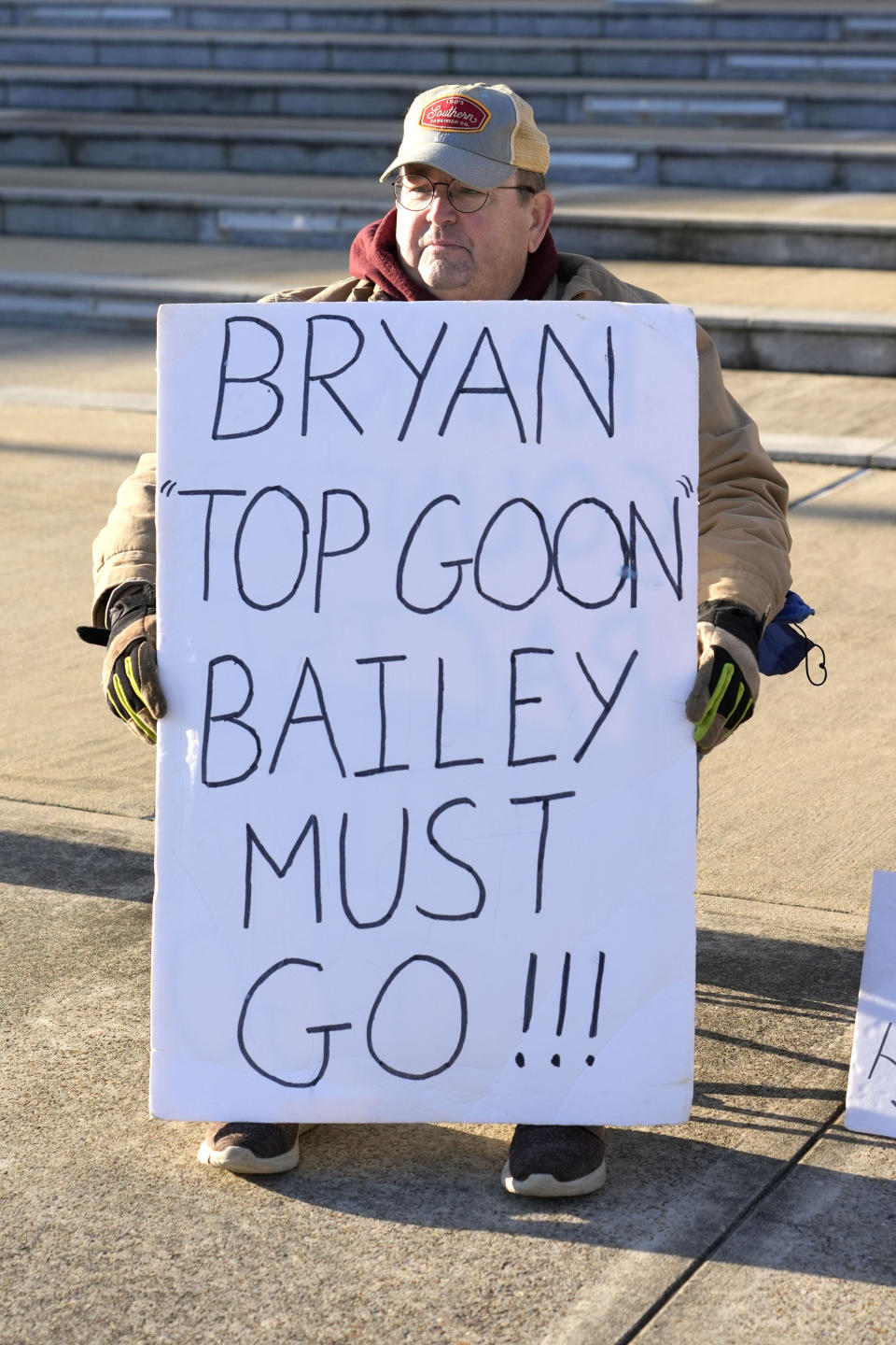 John Osborne, 62, of Jackson, sits outside the Thad Cochran United States Courthouse in Jackson, Miss., Tuesday, March 19, 2024, with a sign calling for the removal of current Rankin County Sheriff Bryan Bailey, in support for the two men abused by then six Mississippi Rankin County law enforcement officers who committed numerous acts of racially motivated, violent torture on Michael Corey Jenkins and his friend Eddie Terrell Parker in 2023. The six former law officers pleaded guilty to a number of charges for torturing them and their sentencing begins Tuesday in federal court. (AP Photo/Rogelio V. Solis)