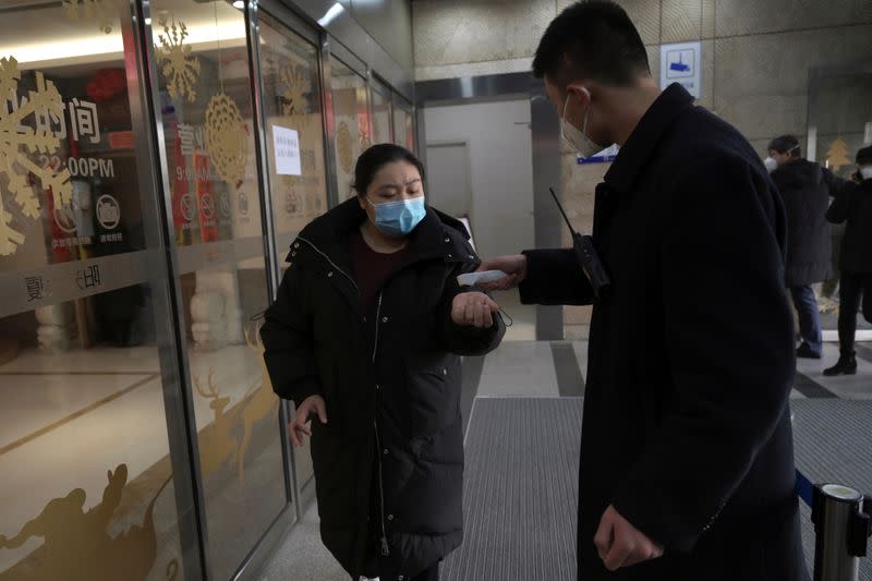 Security personnel checks temperature of a customer entering Alibaba's Hema Fresh chain store, following the coronavirus outbreak, in Beijing