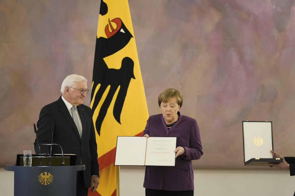 German President Frank-Walter Steinmeier, left, presents the Grand Cross of the Order of Merit of the Federal Republic of Germany in a special design to former Chancellor Angela Merkel, right, during a reception at Bellevue Palace in Berlin, Germany, Monday, April 17, 2023. (AP Photo/Markus Schreiber)