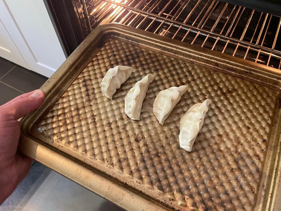 hand putting a tray of potstickers in the oven