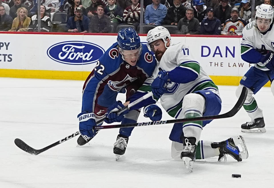 Colorado Avalanche left wing Fredrik Olofsson, left, fights for control of the puck with Vancouver Canucks defenseman Filip Hronek in the first period of an NHL hockey game Tuesday, Feb. 20, 2024, in Denver. (AP Photo/David Zalubowski)