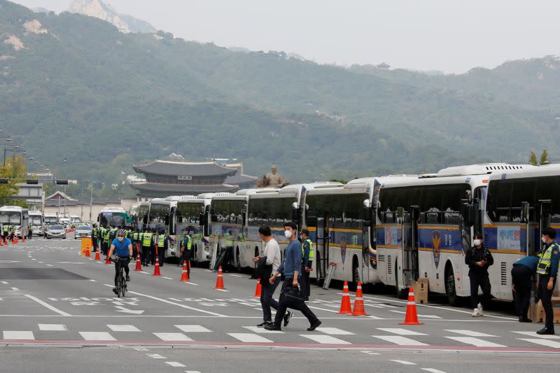 Pedestrians walk past police buses that are parked surrounding the Gwanghwamun square in central Seoul