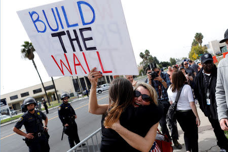 Trump supporters hug after U.S. President Donald Trump's motorcade drove past them following his viewing of border wall prototypes in San Diego, California, U.S., March 13, 2018. REUTERS/Mike Blake