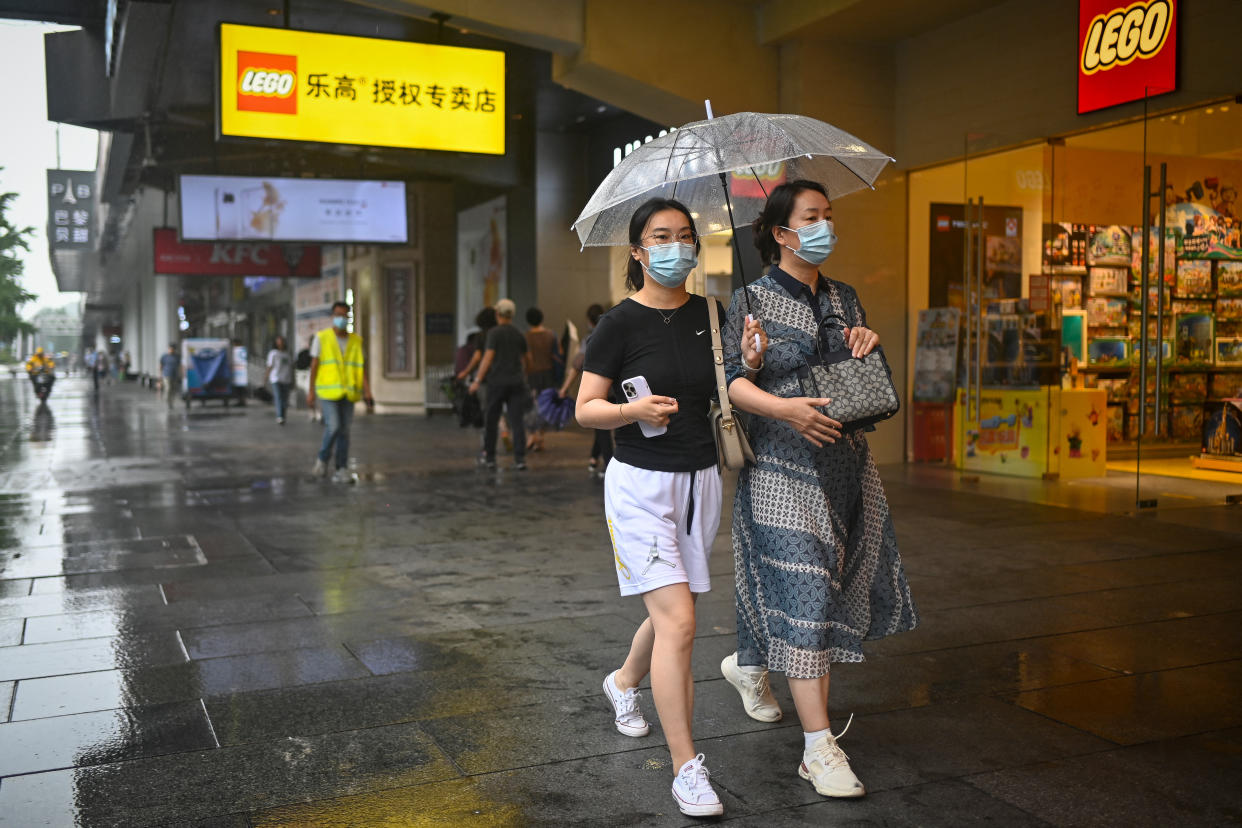 People use an umbrella as they walk past a Lego store on a rainy day in Beijing.