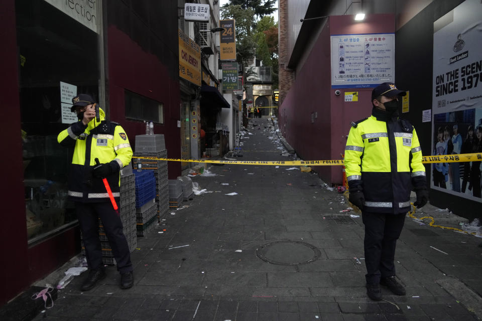 Police officers stand guard at the scene where dozens of people died and were injured in Seoul, South Korea, Sunday, Oct. 30, 2022, after a mass of mostly young people celebrating Halloween festivities in Seoul became trapped and crushed as the crowd surged into a narrow alley. (AP Photo/Ahn Young-joon)