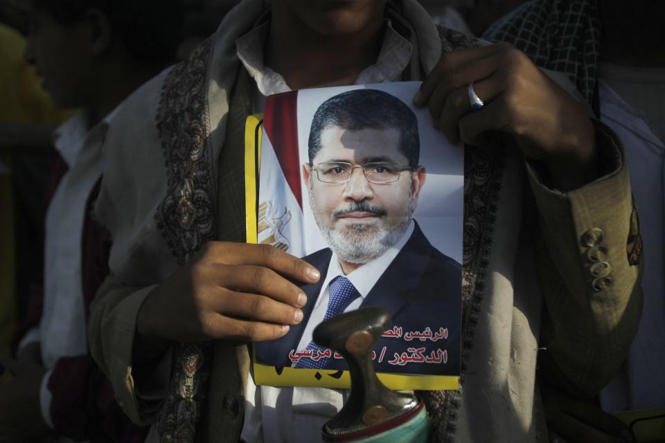 A pro-democracy protester holds a poster of deposed Egyptian President Mohamed Mursi, as he takes part in a demonstration to demand that Yemen's former president Ali Abdullah Saleh be put on trial, in Sanaa September 25, 2013. REUTERS/Khaled Abdullah (YEMEN - Tags: POLITICS CIVIL UNREST)