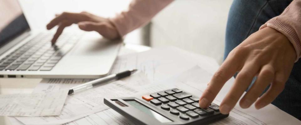 Close up cropped image young woman calculating monthly expenses with calculator and computer