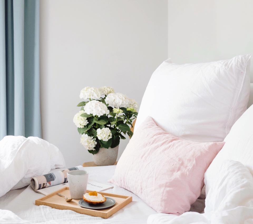 Close-Up Of White Flowers In Vase On Bed