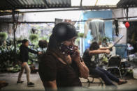 Elisa Xolalpa, who survived an acid attack while tied to a post by her ex-partner 20 years ago when she was 18, talks on a cell phone as her children play at her parents' house in Mexico City, Sunday, July 4, 2021. Xolapa said we can’t allow the violence to be normalized and that’s a message she wants to teach her daughters. (AP Photo/Ginnette Riquelme)