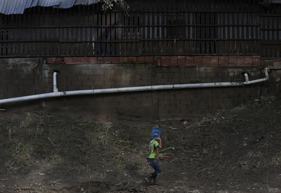 A man carries a container with potable water from a broken pipe connected to a well, to distribute to the community after a landslide ripped through Las Tejerias, Venezuela, Monday, Oct. 10, 2022. The fatal landslide was fueled by days of torrential rain and floods that swept through this town in central Venezuela. (AP Photo/Matias Delacroix)