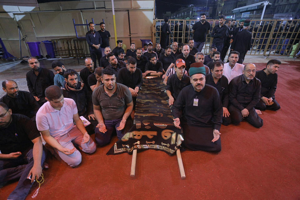 Mourners pray by the coffin of a victim inside the shrine of Imam Abbas after a walkway collapsed and set off a stampede as thousands of Shiite Muslims marked one of the most solemn holy days of the year in the holy city of Karbala, Iraq, Tuesday, Sept. 10, 2019. Officials say at least 31 people have died and around 100 others were injured in the chaos Tuesday, which occurred toward the end of the Ashoura procession, causing panic and a stampede, according to two officials. (AP Photo/Anmar Khalil)