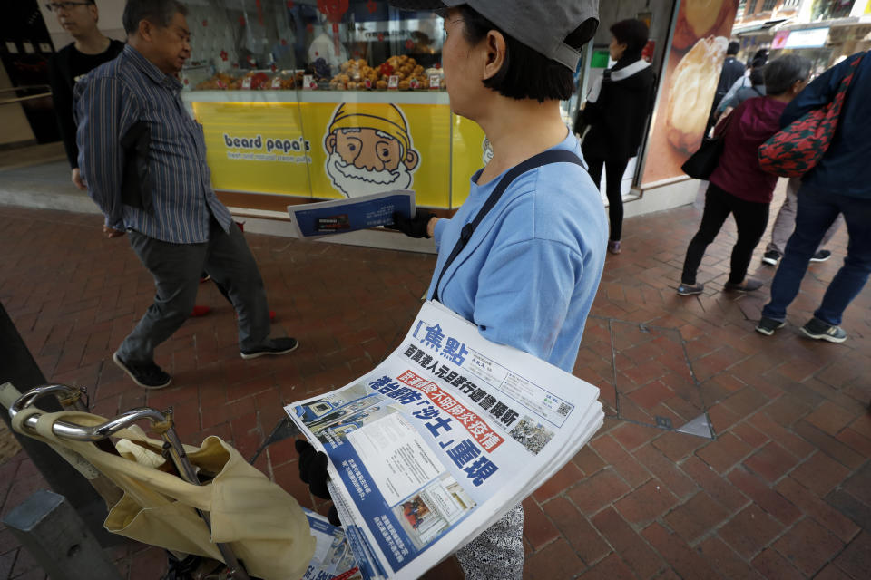 A vendor gives out copies of newspaper with a headlines of "Wuhan break out a new type of coronavirus, Hong Kong prevent SARS repeat" at a street in Hong Kong, Saturday, Jan. 11, 2020. Health authorities in the central Chinese city of Wuhan are reporting the first death from a new type of coronavirus. The Wuhan Municipal Health Commission reported Saturday that seven other people are in critical condition. (AP Photo/Andy Wong)