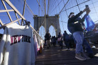 Pedestrians pass by vendors on the Brooklyn Bridge in New York, Tuesday, Jan. 2, 2024. New York City will ban vendors from the Brooklyn Bridge starting Wednesday, Jan. 3, 2024. The move is intended to ease overcrowding on the famed East River crossing, where dozens of souvenir sellers currently compete for space with tourists and city commuters. (AP Photo/Seth Wenig)