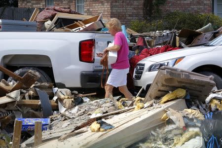 A woman walks through piles of debris in front of flood damaged homes in Prairieville, Louisiana, U.S., August 22, 2016. REUTERS/Jonathan Bachman