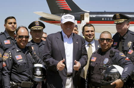 Republican presidential candidate Donald Trump poses with policemen, as he departs Laredo, Texas July 23, 2015. REUTERS/Rick Wilking