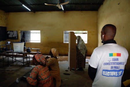 Electoral workers wait as a voter stands at a polling booth during a run-off presidential election in Bamako, Mali August 12, 2018. REUTERS/Luc Gnago