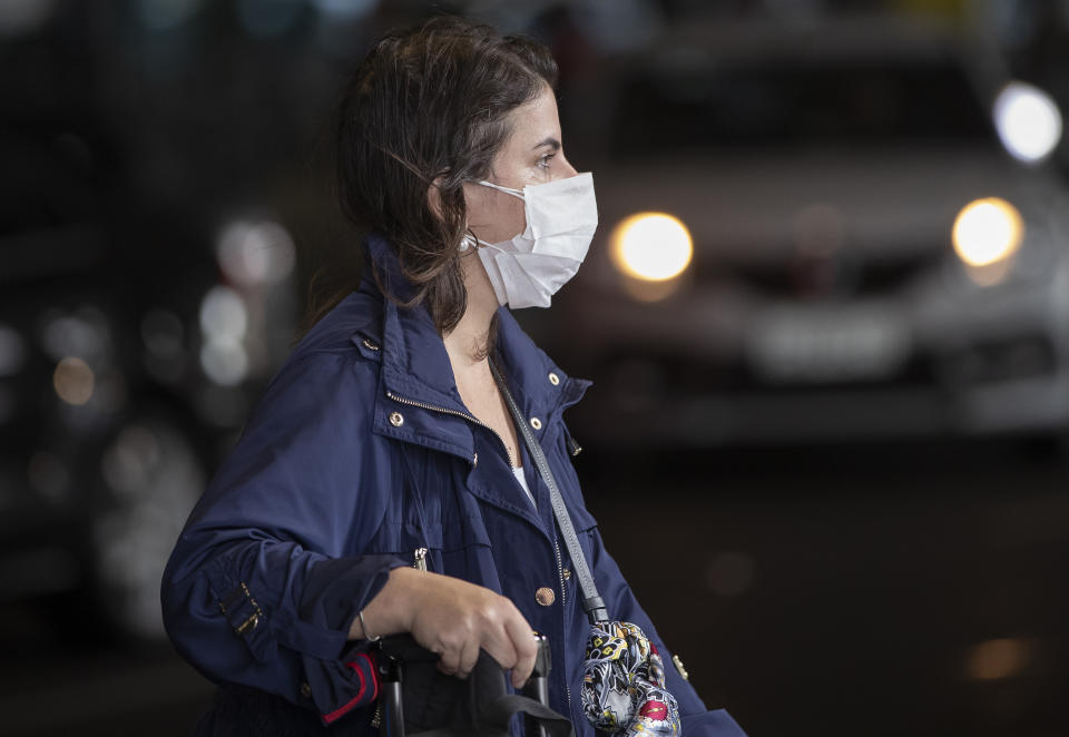 A passenger wearing a mask as a precaution against the spread of the new coronavirus COVID-19 arrives to the Sao Paulo International Airport in Sao Paulo, Brazil, Wednesday, Feb. 26, 2020. (AP Photo/Andre Penner)