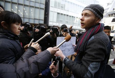 Kolin Burges (R), a self-styled cryptocurrency trader and former software engineer from London, speaks to the media while holding a placard to protest against Mt. Gox, in front of the building where the digital marketplace operator was formerly housed in Tokyo February 26, 2014. REUTERS/Toru Hanai