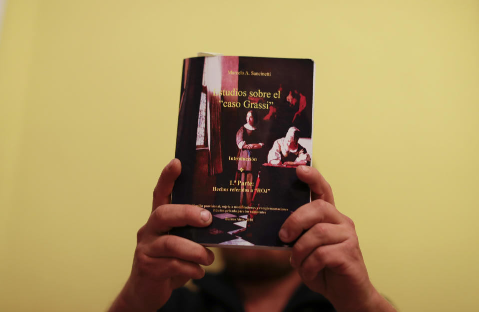 In this Sept. 12, 2018 photo, Gabriel, a sex abuse victim of Rev. Julio Grassi, who did not want to show his face, holds one of four books written by Argentine criminal defense attorney Marcelo Sancinetti, that makes the argument that Grassi is innocent and his victims are lying, in Buenos Aires, Argentina. Gabriel said he is still waiting for Francis to acknowledge his pain, given the Supreme Court has now ruled that he indeed was assaulted by Grassi when he was 13. (AP Photo/Natacha Pisarenko)