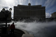 FILE - In this March 16, 2020, file photo, people watch the fountain show at the Bellagio before its closing due to the coronavirus in Las Vegas. Cards will be cut, dice will roll and jackpots jingle when casinos in Las Vegas and Nevada begin reopening at 12:01 a.m. on Thursday, June 4, 2020. There will be big splashes, even amid ongoing unrest, and big hopes for recovery from an unprecedented and expensive closure prompted by the coronavirus pandemic. (AP Photo/John Locher, File)