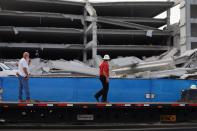 DORAL, FL - OCTOBER 10: Construction workers look on from a flat bed truck at the rubble of a four-story parking garage that was under construction and collapsed at the Miami Dade College’s West Campus on October 10, 2012 in Doral, Florida. Early reports indicate that one person was killed, at least seven people injured and one is still trapped. (Photo by Joe Raedle/Getty Images)