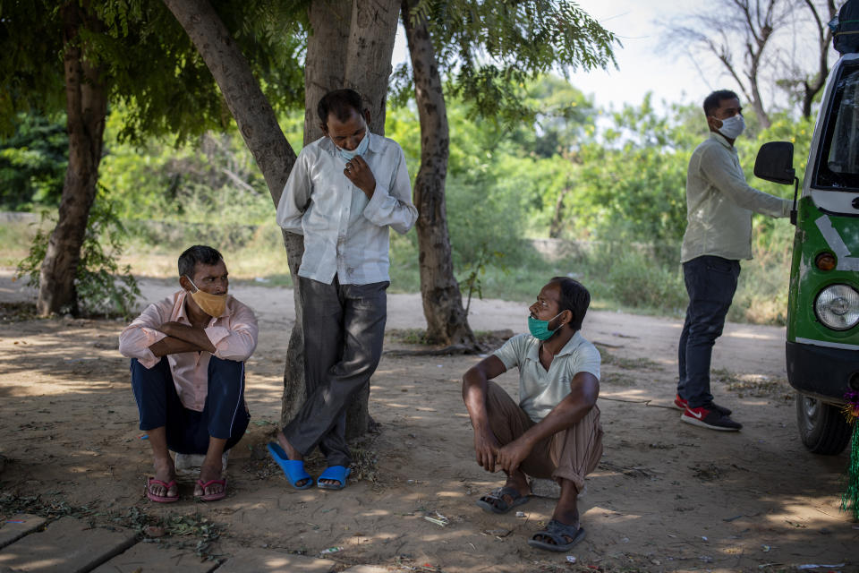 Migrant workers Ram Ratan, center standing, and Mansoor Ansari, seated right, talk sitting by the side of a road as they look for jobs in Manesar, India, Tuesday, Sept. 22, 2020. “There is almost no work,” said Ratan, 46, who was working in a printing company before he returned to his home village in April. Ansari and Ratan are among hundreds of workers who wait every day on what is called a “labor roundabout,” in an industrial area, hoping to get picked up by employers. Before the pandemic lockdown, Ansari had a steady job at a garment factory in the industrial town of Manesar near New Delhi, earning $200 a month, he said. (AP Photo/Altaf Qadri)